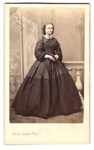 Fotografie Herm. Linde, Lübeck, Johannis-Str. 31, Dame im eleganten Kleid vor Studiokulisse