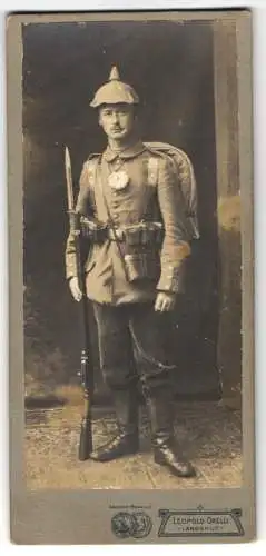 Fotografie Leopold Orelli, Landshut, Soldat in Feldgrau Uniform mit Pickelhaube Tarnbezug, Kriegsausmarsch, Bajonett