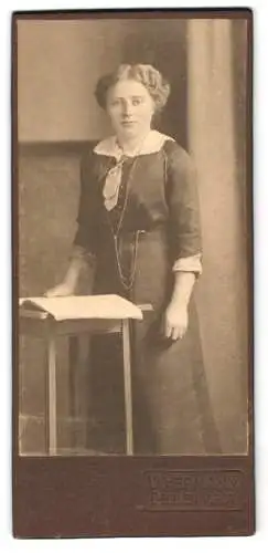 Fotografie V. Hermann, Delmenhorst, Frau in elegantem Kleid an Tisch stehend