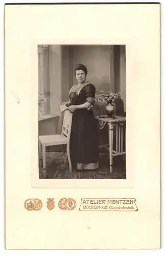 Fotografie Atelier Mentzen, Mülheim-Ruhr, Eppinghoferstr. 26, Dame mit Stuhl in elegantem Kleid