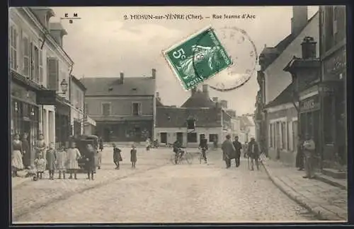 AK Mehun-sur-Yèvre, Rue Jeanne d`Arc animée avec passants et bicyclette