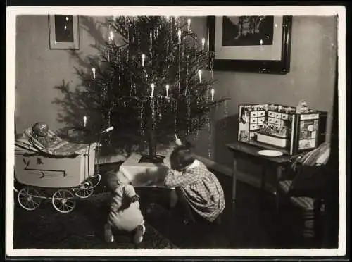 Fotografie unbekannter Fotograf und Ort, Weihnachten Kinder schauen unter den Weihnachtsbaum, Puppenwagen, Puppenstube