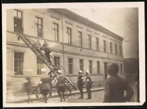 Fotografie unbekannter Fotograf und Ort, Feuerwehrleute beim Einsatz am Rathaus, Leiterwagen