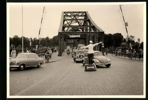 Fotografie unbekannter Fotograf, Ansicht Rendsburg, Verkehrspolizist regelt Verkehr an der Hochbrücke, VW Käfer
