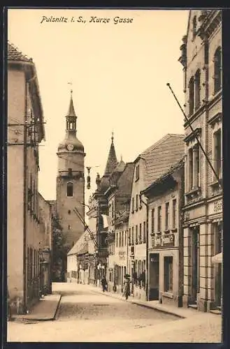 AK Pulsnitz i. S., Strasse Kurze Gasse mit Kirche und Geschäften