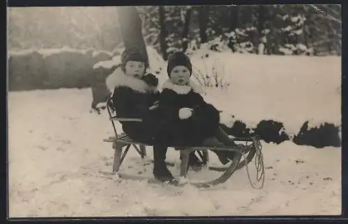 AK Zwei Kinder auf einem Schlitten sitzend