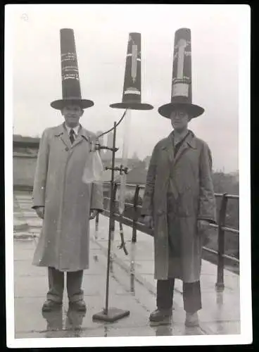 Fotografie unbekannter Fotograf und Ort, zwei Wissenschaftler mit Versuchsaufbau und Pylonen auf dem Kopf