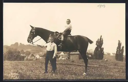 Foto-AK Zwei Knaben mit einem Reitpferd vor einer Ortschaft