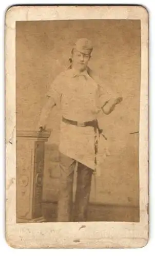 Fotografie unbekannter Fotograf und Ort, junger Fleischer mit Axt und Wetzstahl