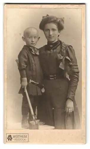 Fotografie Wertheim, Rostock, junger Knabe mit Glatzkopf nebst seiner Mutter im dunklen Kleid mit Zopf