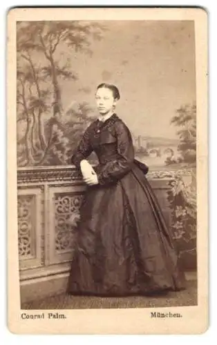 Fotografie Conrad Palm, München, Sonnenstr. 7, Portrait hübsche junge Frau im schwarzen Kleid vor Studiokulisse