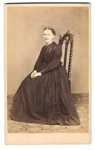 Fotografie J. Holms, Faaborg, Portrait junge Frau im schwarzen Kleid auf Stuhl sitzend