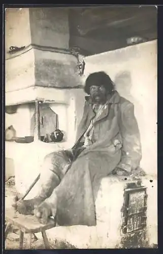 Foto-AK Russischer Bettler wärmt sich an einem Ofen