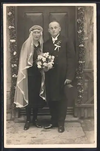 Foto-AK Braut und Bräutigam vor einer geschmückten Tür