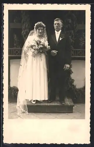 Foto-AK Brautpaar mit Blumenstrauss auf einem Podest
