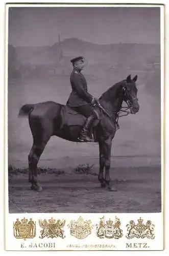 Fotografie E. Jacobi, Metz, Offizier in Uniform zu Pferde vor einer Stduikulisse