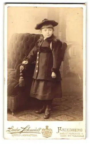 Fotografie Ludw. Schmidt, Friedberg / Hessen, junges Schulmädchen mit Ranzen im dunklen Winterkleid