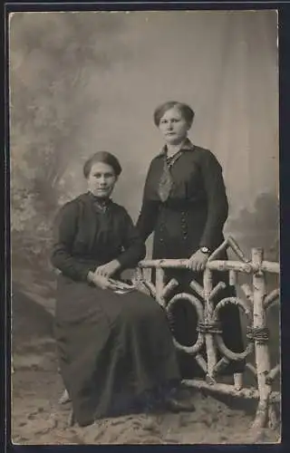 Foto-AK Zwei Frauen in dunklen Kleidern in einer Studiokulisse