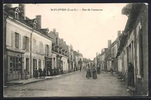 AK St-Flovier, Rue du Commerce animée avec passants et bâtiments historiques