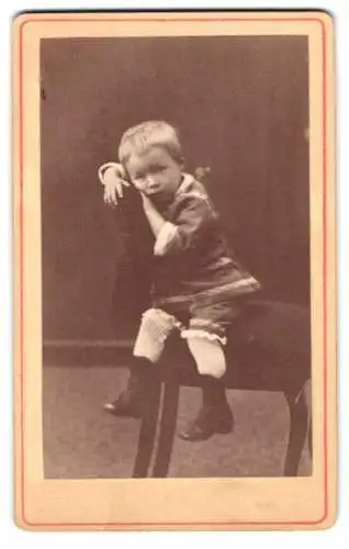 Fotografie unbekannter Fotograf und Ort, niedliches kleines Kind sitzt lässig auf einem Stuhl