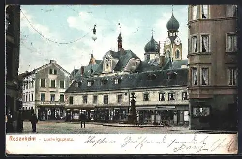 AK Rosenheim, Ludwigsplatz mit Warengeschäften, Brunnen und Blick auf Kirchturm