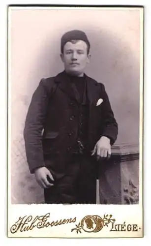 Fotografie Hub. Goossens, Liège, Rue Louvrex 4, Junger Mann in Anzug mit Mütze
