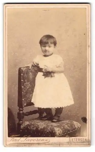 Fotografie Ferd. Lavorenz, Uetersen, Gr. Wulfhagen 4, Kind in festlichem Kleid auf Stuhl