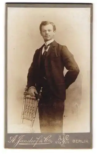 Fotografie A. Jandorf & Co., Berlin, Leipziger-Strasse 64, Elegant gekleideter Herr mit Stuhl