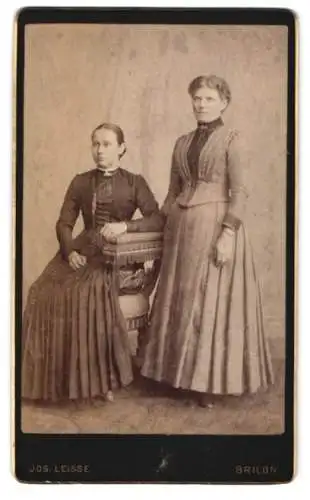 Fotografie Jos. Leisse, Brilon, Sitzende und stehende Dame in taillierten Kleidern