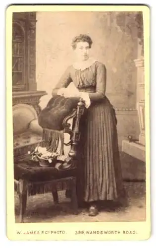 Fotografie W. James & Co., London, Wandsworth Road 399, Elegante Dame stehend mit Stuhl