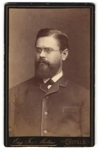 Fotografie Eug. Jos. Mertens, Crefeld, Hochstrasse 68, Porträt eines bärtigen Mannes mit Brille
