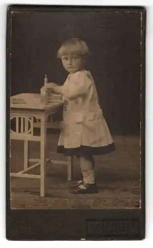 Fotografie J. Mürnseer, Karlsruhe, Kind mit Spielzeug am Tisch