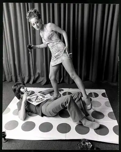 Fotografie Eric Wilkins, junges Paar spielt eine Runder Twister, Frau im Minikleid, Grossformat 20 x 25cm