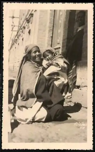 Fotografie Chilenische Mutter mit ihrem Kind im Arm hockt auf der Strasse, Chile