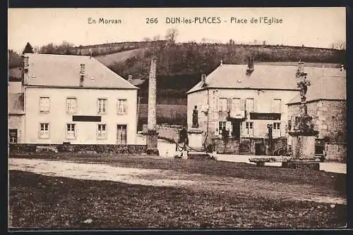AK Dun-les-Places, Place de l`Église avec bâtiments et monument en arrière-plan