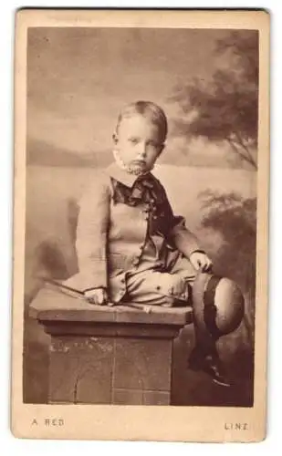 Fotografie August Red, Linz, Portrait junger Knabe Oskar im Anzug mit Hut und Stock