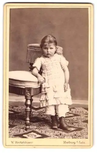Fotografie W. Hertzhäuser, Marburg a. Lahn, Ketzerbach, Kind in weissem Kleid neben Stuhl