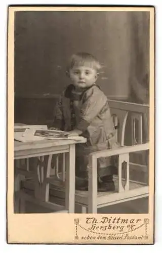 Fotografie Th. Dittmar, Herzberg a. E., Porträt eines Kindes am Tisch