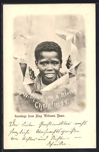 AK King Williams Town, Afrikanischer Junge durch zerrissenes Papier, afrikanische Volkstypen, Weihnachtsgruss