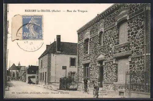 AK Marigny-le-Châtel, Rue de Troyes avec bâtiments en pierre et cyclistes