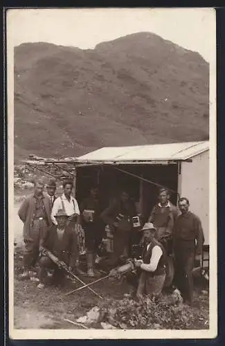 Foto-AK Strassenbau-Arbeiter mit Bohrern vor einer Hütte im Gebirge, Gruppenfoto