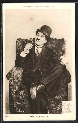 AK Schauspieler Charles Chaplin sitzt mit Weinglas auf einem Sessel