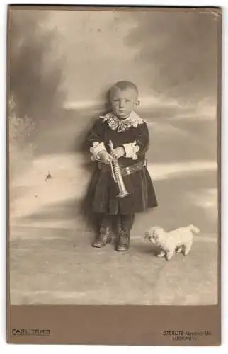 Fotografie Carl Trieb, Steglitz, kleines Kind im Samtkleid mit Trompete und Stoffhund