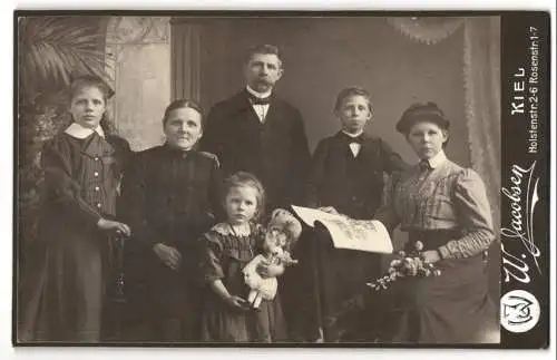 Fotografie W. Jacobsen, Kiel, Familie mit Tochter samt Puppe im Arm