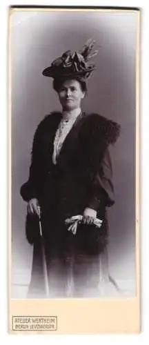 Fotografie Wertheim, Berlin, Dame im Kleid mit Fellbesatz und Federhut hält Schirm in der Hand