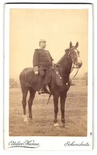 Fotografie Atelier Kunze, Schweidnitz, korpulenter Offizier in Uniform zu Pferde mit Orden an der Brust und Pickelhaube