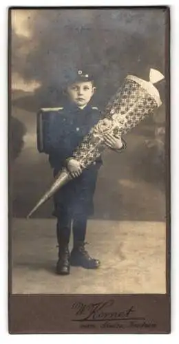Fotografie W. Kornet, Bautzen, junger sächsischer Knabe zum Schulanfang mit riesiger Zuckertüte und Ranzen