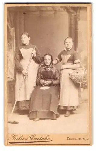 Fotografie Julius Grusche, Dresden, Dienstmädchen als Köchin, mit Besen und Einkaufskorb, Dienstmagd