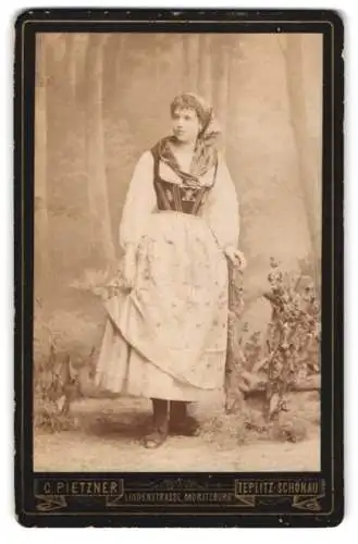 Fotografie C. Peitzner, Teplitz-Schönau, junge Frau in Tracht vor einer Studiokulisse