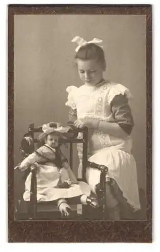 Fotografie unbekannter Fotograf und Ort, Mädchen mit ihrer grossen Puppe auf dem Stuhl